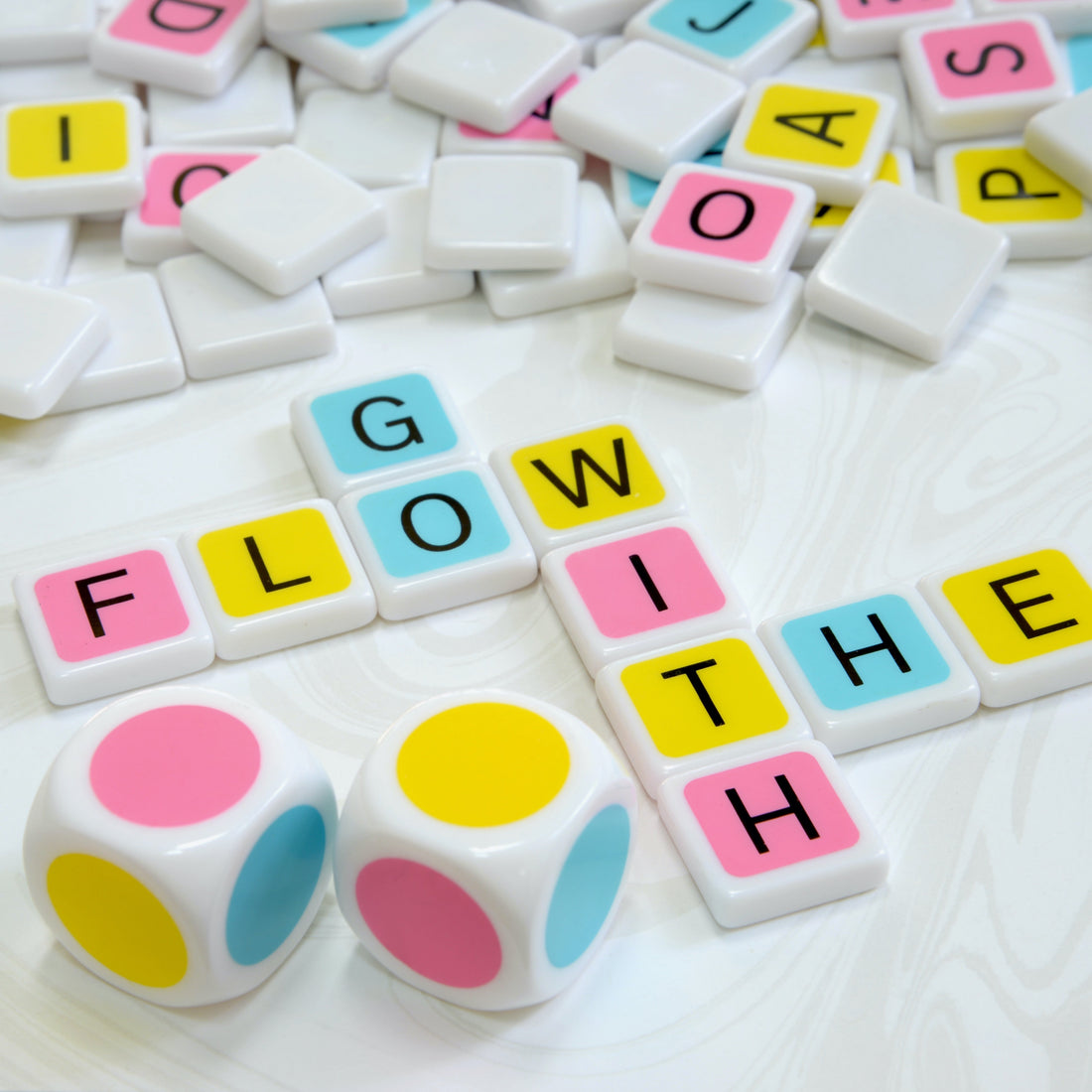 Candygrams “the colorful crossword game” is the perfect combination of skill, strategy, and luck. large colorful dice along with a colorful letter tile crossword spelling ‘go with the flow’ on a swirling white background