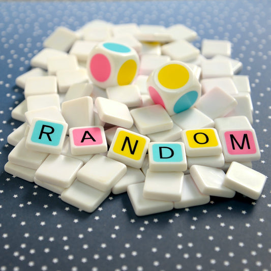 Random makes Candygrams a great board game. large colorful dice along with colorful letter tiles spelling ‘random’ on a blue polka dot background