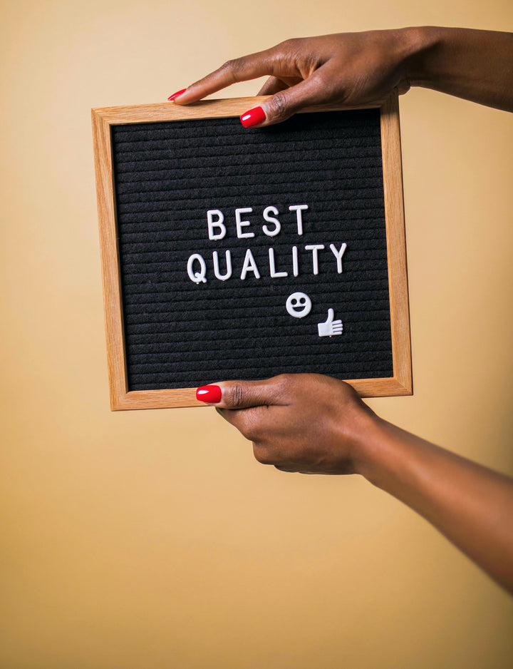 family board game with quality components over hands holding a letter board with 'BEST QUALITY' text on a beige background