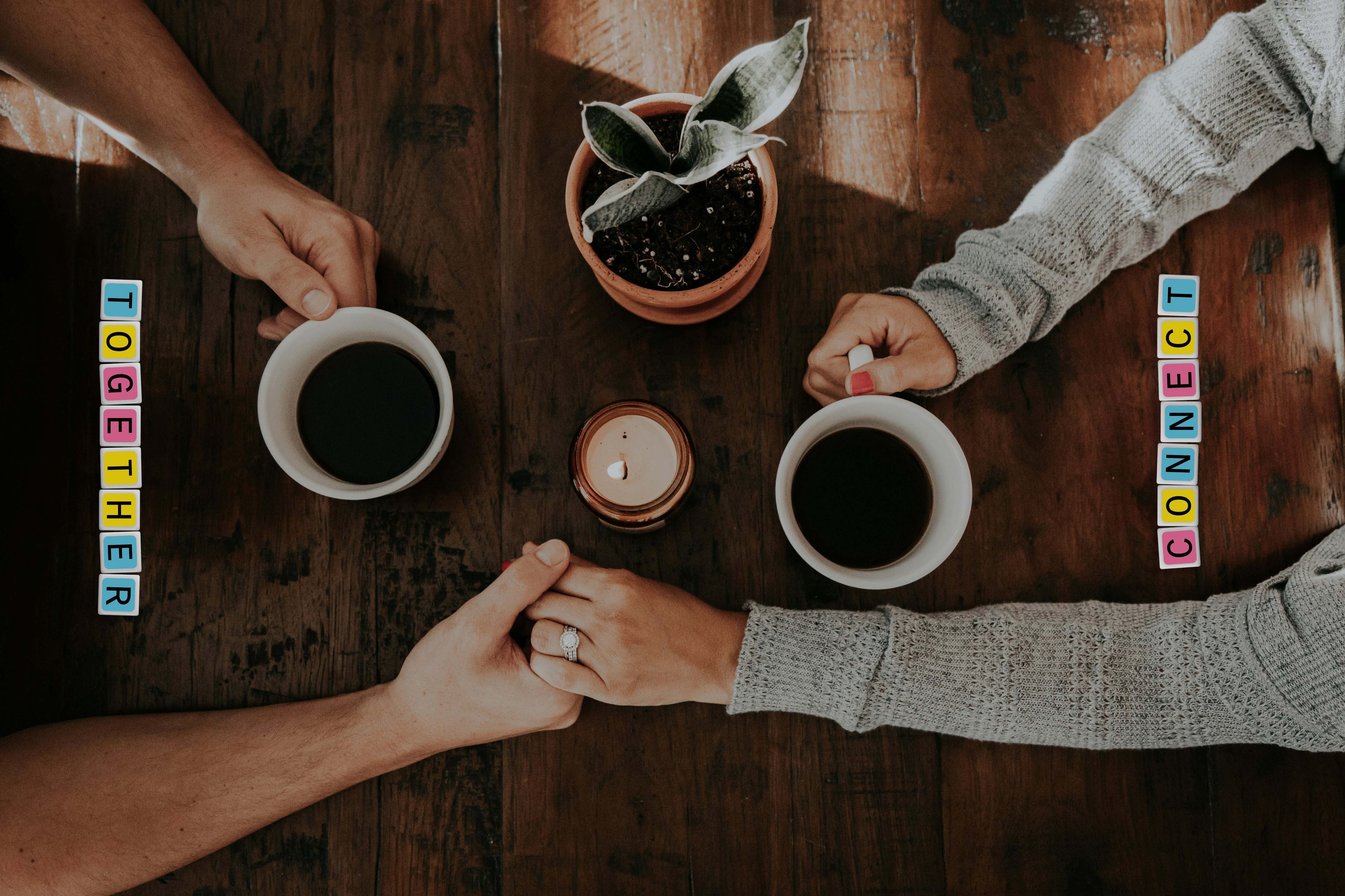 candygrams word game with two people holding hands over coffee cups on a wooden table with 'Together' and 'Connected' letter tiles