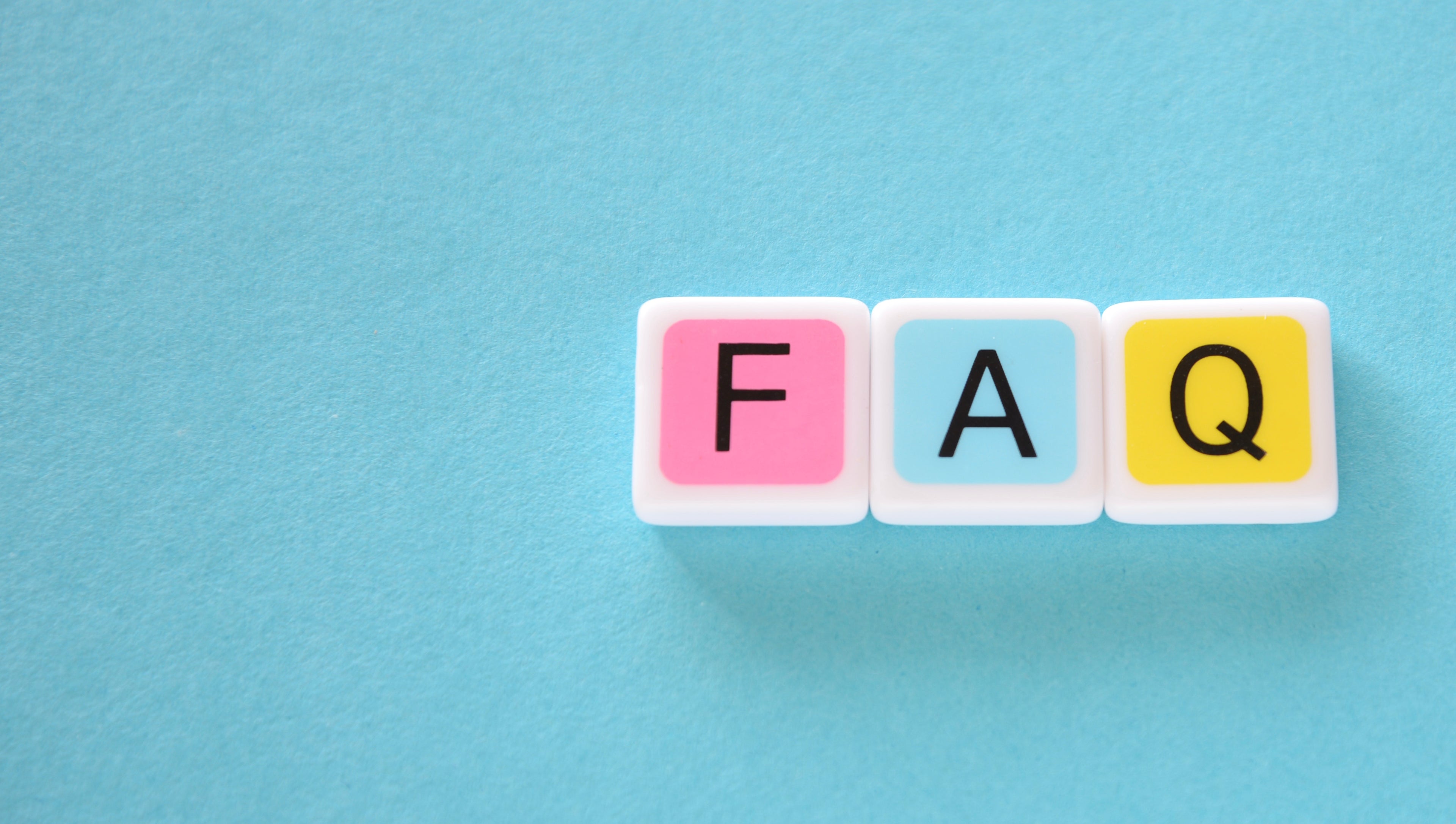 candygrams word game ‘FAQ' crossword made with colorful letter tiles and pastel colored dice over a blue background